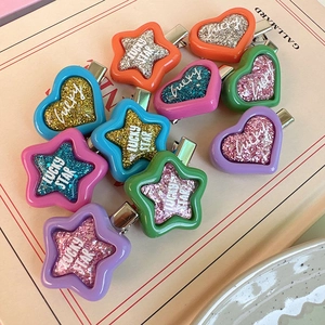 Detail of candy-colored Y2K star hair clips with glitter layers and Lucky Star text