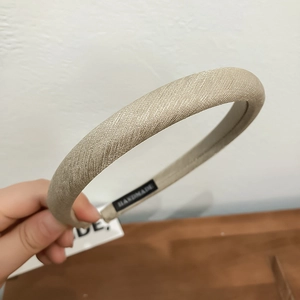 Detail of handmade padded headband with champagne gold textured fabric and inner label