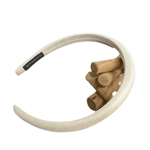 Minimalist white fabric headband with textured finish and handmade label on white background