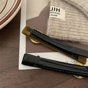 Detail of velvet hair clips with golden buttons on a wooden desk with a knitted hat