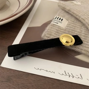 Close-up of black velvet hair clip with a gold metal buckle on a cozy knit background