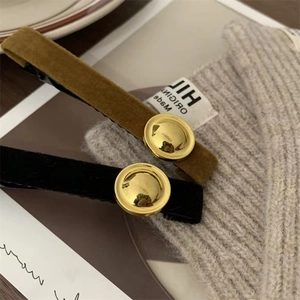 Detail view of mustard yellow and black velvet hair clips with golden buckle accents