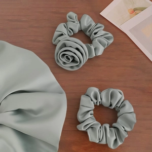 Elegant grey satin scrunchie set with rose flower detail on a rustic wood surface