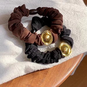 Detailed close-up of brown and black scrunchies with polished gold buckle decorations
