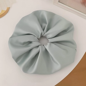 Macro detail of a large satin scrunchie in light blue with elegant pleated texture