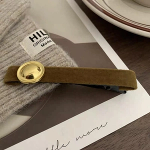 Retro velvet hair clip in olive brown with golden metal button on grey knitwear