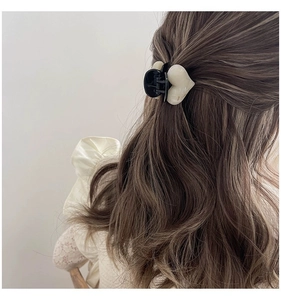 Détail d'une pince à cheveux en forme de cœur à motif marbré sur une queue de cheval