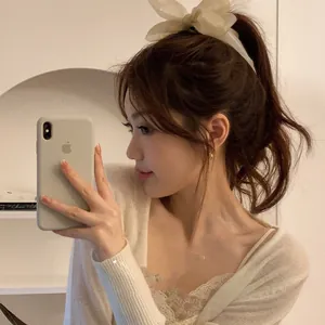 Detailed view of an oversized beige chiffon bow banana clip worn in a high ponytail hairstyle