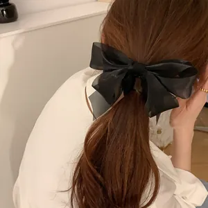 Detail of a large black organza bow hair clip on a ponytail with sheer layered fabric