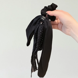 Elegant black lace bow scrunchie with silk-like ribbon detail and handmade tag