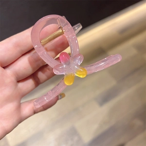 Detail of pink jelly hair claw clip with colorful floral accent and gold metal spring
