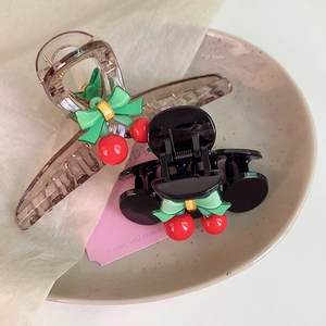 Detailed view of sweet cherry and bow hair claws on a decorative ceramic plate