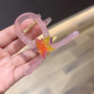 Close-up of pink translucent heart hair claw clip with a gradient star and gold spring detail