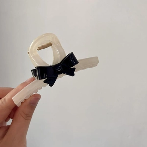Elegant cream resin shark hair claw clip with a glossy black contrast bow design