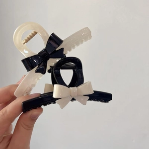 Elegant black and cream bow hair claws with glossy finish in a minimalist shark clip style