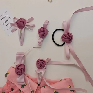 Detail von rosa Stoffrosen-Haarspange und Schleifen-Set auf weißem Grund