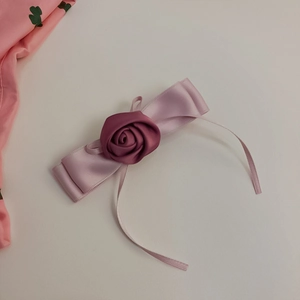 Eleganter Haarclip aus rosa Satin mit Stoffrose auf einem sauberen weißen Hintergrund