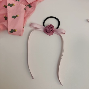 Detail einer eleganten rosa Satin-Rosen-Haarklammer mit langen Bändern auf Weiß