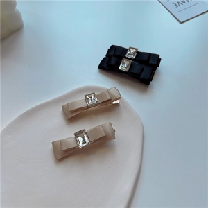 Detailed set of black and champagne satin bow hair clips with rectangular crystals