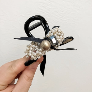 Détail de la pince à cheveux française avec perles, nœud noir et ornements de bijoux