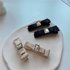 Detail of vintage bow hair clips with rectangular crystals on a white ceramic tray
