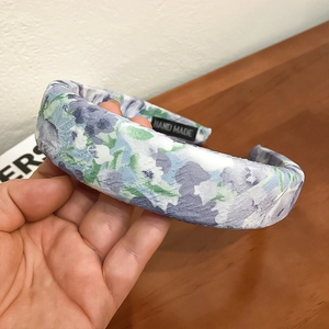 Close-up of thick floral cloth headband with handmade label and watercolor pattern