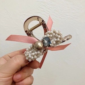 Détail de la pince à cheveux style français avec nœud rose, perles et gemme en cristal
