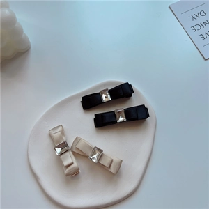 Detail of silk bow hair clips set with square crystals in black and beige tones
