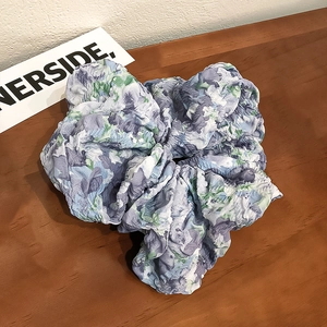 Floral print scrunchie in purple and blue textured seersucker fabric on a wooden table