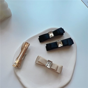 Detail view of the black and beige satin bow hair clips with rectangle crystal rhinestones