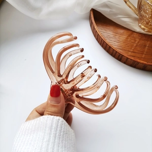 Detail of amber translucent hair claw clip with multi-tooth design on a wooden tray
