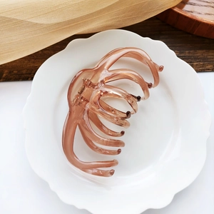Close-up of translucent brown octopus hair claw clip on a white ceramic flower plate