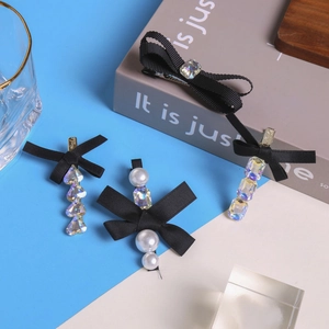 Detail van zwarte haarklemmen met strikjes, strass en parels op een esthetische achtergrond