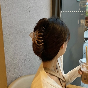 Detail view of transparent amber claw clip holding hair in a French lazy bun style