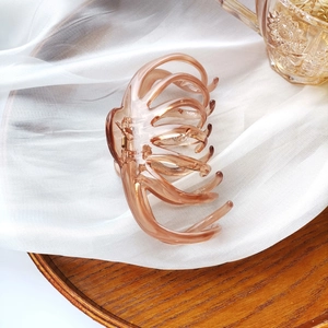 Detail of an amber oversized hair claw with a unique octopus design on white fabric