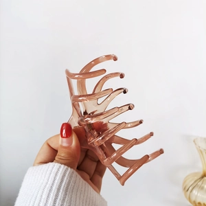 Close-up of a large amber translucent octopus claw clip held by a hand for elegant styling
