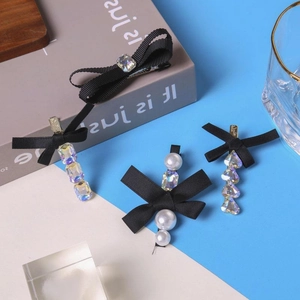 Stijlvolle zwarte strik haarspelden met strass en parels op blauwe achtergrond