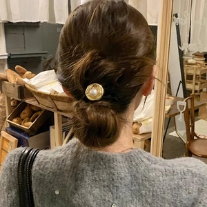 Close-up of vintage pearl hair tie with irregular gold metal base on a bun hairstyle