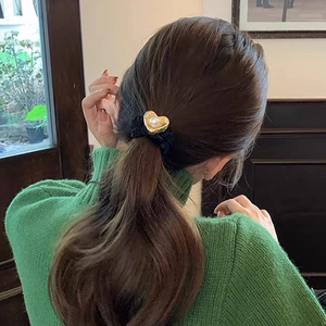 Detail of vintage heart pearl hair scrunchie shown on a low ponytail with green knitwear