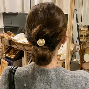 Vintage pearl hair tie with gold metallic base worn on a low bun hairstyle