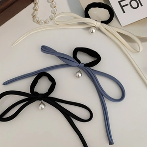 Close-up of three satin bow hair ties in white, blue and black with pearl charms