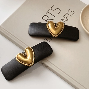 Detail of two black PU leather rectangle hair clips with golden heart metal ornaments