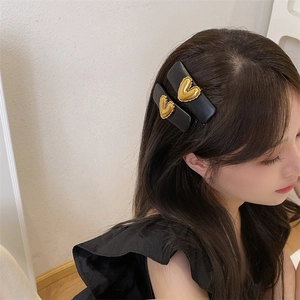 Detail view of black PU leather sponge BB clips with embossed gold heart metal accents