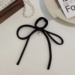 Detail of elegant black fabric bow hair tie with a single pearl pendant and silver base