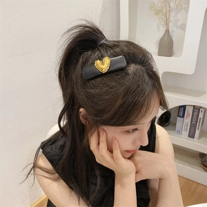 Detailed view of a vintage black leather hair clip with a gold heart on a model