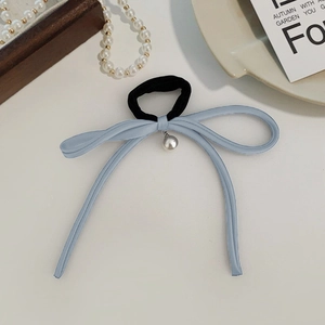 Close-up of blue satin bow hair tie with pearl charm pendant on elegant background