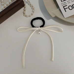 Close-up of elegant French style black hair tie with cream bow and pearl pendant detail
