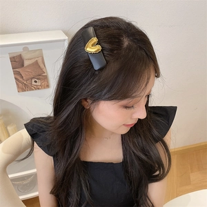 Detail of vintage gold heart hair clip with black PU leather base on model's hair