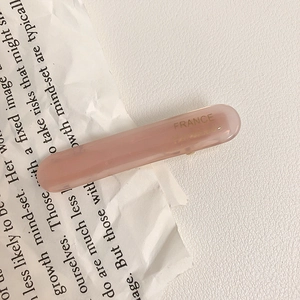 Elegant rectangular pink acetate hair clip with gold handmade lettering on white book