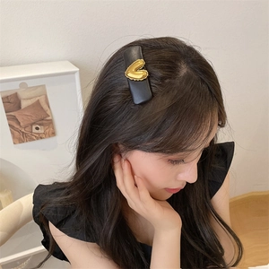 Close-up of a model wearing a black leather hair clip with a golden heart detail